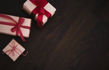 Noel hediyeleri ve geleneksel bayram hediyeleri, ahşap arka planda klasik Noel hediyesi kutuları, kırmızı kurdeleyle sarılmış el işi kağıtları, mevsimsel tatiller için klasik kır tarzı.