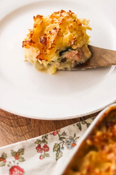 Comfort food and traditional English cuisine, portion of fish pie served on white plate on rustic wooden table, homemade recipe idea