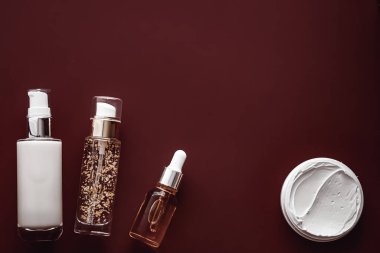 Cilt bakım ürünleri ve yaşlanmayı önleyen güzellik ürünleri, lüks cilt bakım şişeleri, yağ, serum ve çikolata arka planında yüz kremi..