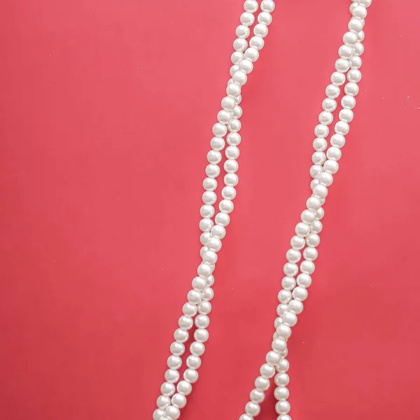 Pearl jewellery necklace on coral background.