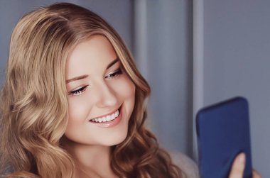 Güzel bir kadın cep telefonuyla video görüşmesi yapıyor, akıllı telefondan online alışveriş yapıyor..