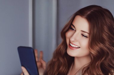 Güzel bir kadın cep telefonuyla video görüşmesi yapıyor, akıllı telefondan online alışveriş yapıyor..