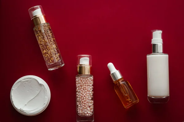 Skincare cosmetics and anti-aging beauty products, luxury skin care bottles, oil, serum and face cream on red background.