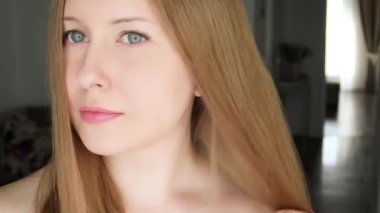 Beautiful happy woman combing her long blond hair.