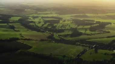 Aerial view of rolling hills of the English countryside landscape, beautiful nature, rural fields and green pastures on a sunny day in England, United Kingdom.