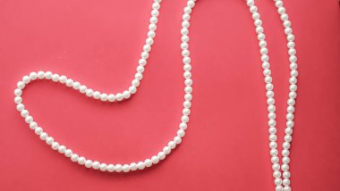Pearl jewellery necklace on coral background. clipart