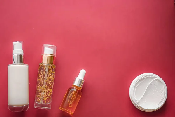 Skincare cosmetics and anti-aging beauty products, luxury skin care bottles, oil, serum and face cream on coral background.
