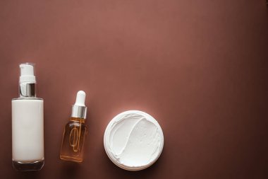 Skincare cosmetics and anti-aging beauty products, luxury skin care bottles, oil, serum and face cream on brown background.