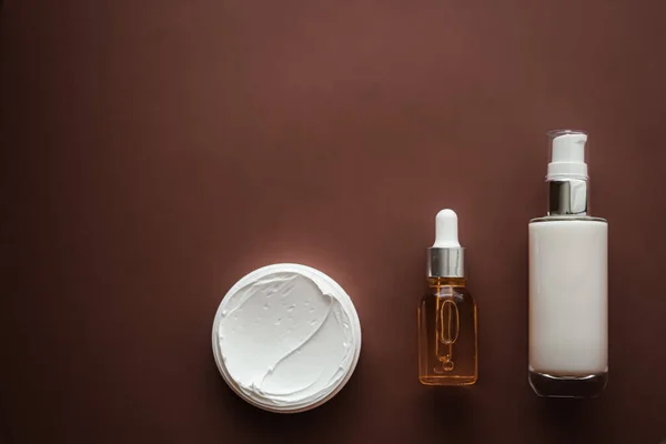 Skincare cosmetics and anti-aging beauty products, luxury skin care bottles, oil, serum and face cream on brown background.