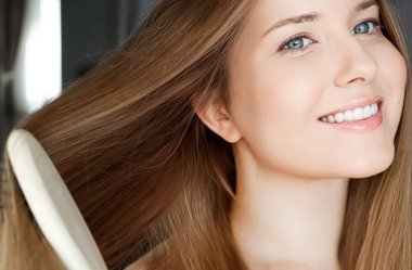Beautiful happy woman combing her long hair.