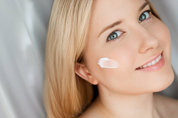 Красивая женщина с кремом для кожи на лице.