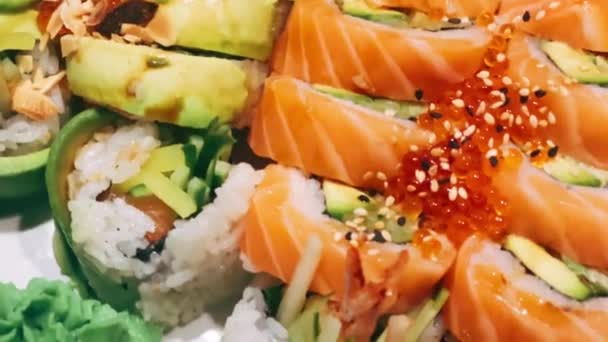 日本料理店の寿司皿のクローズアップでは 角皿の上に様々な寿司がきれいに並べられています 寿司の鮮やかな色彩と複雑なディテールを紹介します — ストック動画