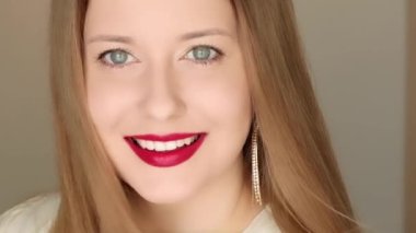 Mükemmel beyaz dişli gülümseyen mutlu bir kadın yakın plan portre içinde poz veriyor, uzun saçlı, altın küpeli ve kırmızı rujlu bir kadın model, mücevher modası ve güzellik..