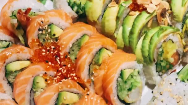 传统的日本寿司 配以新鲜鲑鱼 金枪鱼和鳄梨 在寿司餐厅 健康美味的午餐或晚餐中享用 — 图库视频影像