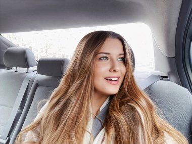 Uzun saçlı genç kadın, arabada dalgalı saç stili ya da yolcu olarak taksi, şehri keşfetme, ulaşım ve seyahat fikri.