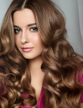 Kıvırcık saçlı, uzun saçlı, güzel makyajlı, lüks moda ve doğal kozmetik fikri olan güzel bir kadın.