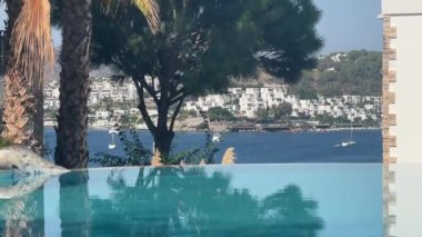 Lüks villa deniz tatil köyünde sonsuz yüzme havuzu manzarası, durgun kristal mavi su ve yaz rahatlaması, yavaş çekim video