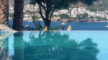Lüks villa deniz tatil köyünde sonsuz yüzme havuzu manzarası, durgun kristal mavi su ve yaz rahatlaması, yavaş çekim video