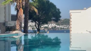 Lüks villa deniz tatil köyünde sonsuz yüzme havuzu manzarası, durgun kristal mavi su ve yaz rahatlaması, yavaş çekim video