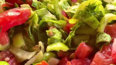 Bir kase taze bahçe salatası, olgun domatesler, taze yeşiller ve biberler, gün batımında deniz kenarında servis edilir, yavaş çekim video.