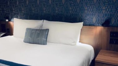 Modern otel odası, modern sanat deco tasarımı, geometrik desenli duvar kağıdı ve dekoratif yastıklı yatak, yavaş çekim video