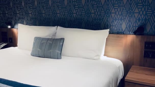 モダンなホテルの客室 コンテンポラリーアートデコデザイン 幾何学模様の壁紙と装飾的な枕付きのベッド スローモーションビデオ — ストック動画