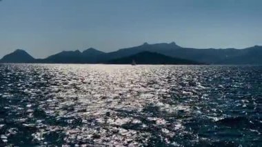 Mavi suları, uçurumları ve gün batımında dağları olan kıyı sahili, yaz tatili.