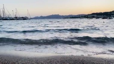 Alacakaranlıkta, yaz tatili seyahatinde, yumuşak dalgalar çakıllı bir plajın üzerinde süzülür. Yüksek kalite 4k görüntü