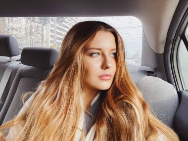 Uzun saçlı genç kadın, arabada dalgalı saç stili ya da yolcu olarak taksi, şehri keşfetme, ulaşım ve seyahat fikri.