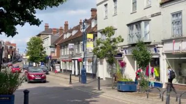 ALTON, HAMPSHIRE, İngiltere - 17 Temmuz 2024: Tarihi binalar, hareketli bir sokak manzarası, canlı çiçekler, somut İngiliz cazibesinin vücut bulmuş hali