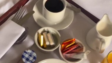 Mısır gevreği, kruvasan, bir bardak portakal suyu, kahve ve bir sürü reçel içeren geleneksel kıtasal kahvaltı seti, hepsi beyaz çarşaflı bir tepside güzelce sunuluyor. Yüksek kalite 4k görüntü