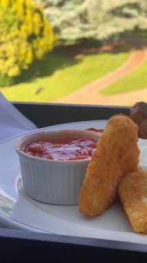 Patates kızartması, mantar, domates, sosis ve fırında fasulye içeren İngiliz kahvaltı tarifi, arka planda manzaralı kırsal bir manzara ile beyaz bir tabakta servis ediliyor. Yüksek kalite 4k görüntü