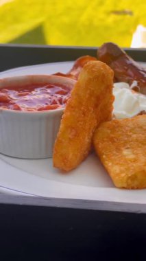 Patates kızartması, mantar, domates, sosis ve fırında fasulye içeren İngiliz kahvaltı tarifi, arka planda manzaralı kırsal bir manzara ile beyaz bir tabakta servis ediliyor. Yüksek kalite 4k görüntü