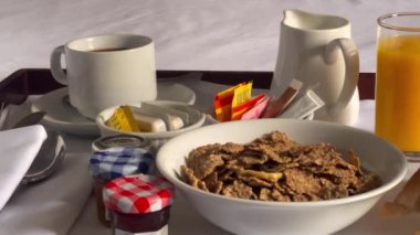 Mısır gevreği, kruvasan, bir bardak portakal suyu, kahve ve bir sürü reçel içeren geleneksel kıtasal kahvaltı seti, hepsi beyaz çarşaflı bir tepside güzelce sunuluyor. Yüksek kalite 4k görüntü