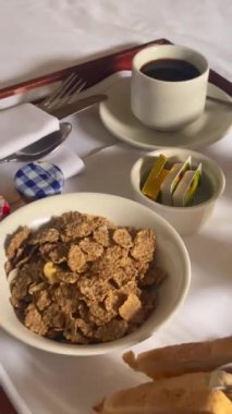 Mısır gevreği, kruvasan, bir bardak portakal suyu, kahve ve bir sürü reçel içeren geleneksel kıtasal kahvaltı seti, hepsi beyaz çarşaflı bir tepside güzelce sunuluyor. Yüksek kalite 4k görüntü