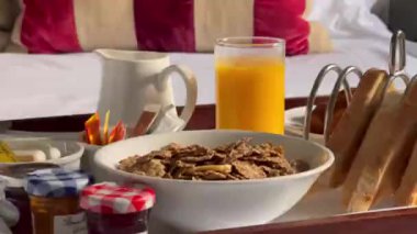 Mısır gevreği, kruvasan, bir bardak portakal suyu, kahve ve bir sürü reçel içeren geleneksel kıtasal kahvaltı seti, hepsi beyaz çarşaflı bir tepside güzelce sunuluyor. Yüksek kalite 4k görüntü