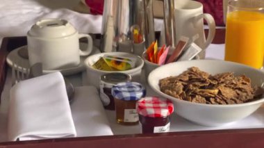 Mısır gevreği, kruvasan, bir bardak portakal suyu, kahve ve bir sürü reçel içeren geleneksel kıtasal kahvaltı seti, hepsi beyaz çarşaflı bir tepside güzelce sunuluyor. Yüksek kalite 4k görüntü