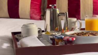 Mısır gevreği, kruvasan, bir bardak portakal suyu, kahve ve bir sürü reçel içeren geleneksel kıtasal kahvaltı seti, hepsi beyaz çarşaflı bir tepside güzelce sunuluyor. Yüksek kalite 4k görüntü