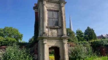 Eski bir taş yapıyı çevreleyen yemyeşil ve renkli çiçeklerle geleneksel kır cazibesini somutlaştıran tarihi İngiliz bahçesi. Yüksek kalite 4k görüntü