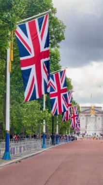 Union Jacks serisi The Mall Buckingham Sarayı 'na gidiyor. Victoria Anıtı, dramatik bir Londra seması altında altın renginde parıldıyor. Yavaş çekim.