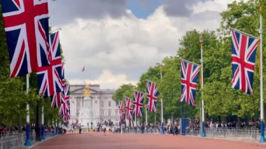 Union Jacks serisi The Mall Buckingham Sarayı 'na gidiyor. Victoria Anıtı, dramatik bir Londra seması altında altın renginde parıldıyor. Yavaş çekim.