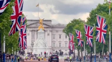 Union Jacks serisi The Mall Buckingham Sarayı 'na gidiyor. Victoria Anıtı, dramatik bir Londra seması altında altın renginde parıldıyor. Yavaş çekim.