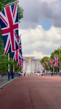 Union Jacks serisi The Mall Buckingham Sarayı 'na gidiyor. Victoria Anıtı, dramatik bir Londra seması altında altın renginde parıldıyor. Yavaş çekim.