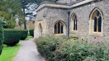 Sivri uçlu kemerli pencereli ve karmaşık detaylarıyla büyüleyici taş kilise, yemyeşil ve huzurlu bir yol ile çevrili, zamansız İngiliz mirasını yansıtıyor.