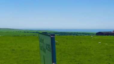 Eastbourne yakınlarındaki İngiliz kırsalında, Doğu Sussex, Birleşik Krallık, sakin kıyı şeridine karışan yemyeşil alanlar ve parlak bir gökyüzü altında sakin mavi deniz