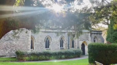 Kemerli pencereleri, taş duvarları ve ağaçlarla çevrili huzurlu bir bahçe yolu dallardan süzülen, dingin ve ebedi bir ortam yaratan İngiliz kırsal kilisesi.
