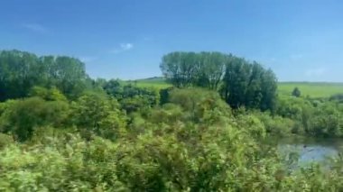 Parlak mavi gökyüzünün altında yuvarlanan yeşil tepeler, İngiliz kırsalının barışçıl güzelliğini gözler önüne seriyor, tren yolculuğu