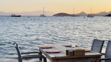 Deniz kenarındaki dört kişilik yemek masası sakin ve romantik deniz manzaralı bir yemek için mükemmel bir ortam sunuyor.