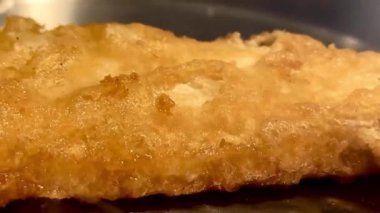 Kıtır kıtır altın renginde balık usulca cızırdar, geleneksel ve rahatlatıcı İngiliz yemeğinin özünü somutlaştırır, İngiliz balık ve patates kızartması.