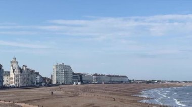 Eastbourne, Doğu Sussex, Birleşik Krallık, büyüleyici İngiliz kıyısı ikonik Viktorya dönemi mimarisi kumlu plajı kaplıyor, yumuşak dalgalar parlak mavi bir gökyüzü altında kıyıya vuruyor,